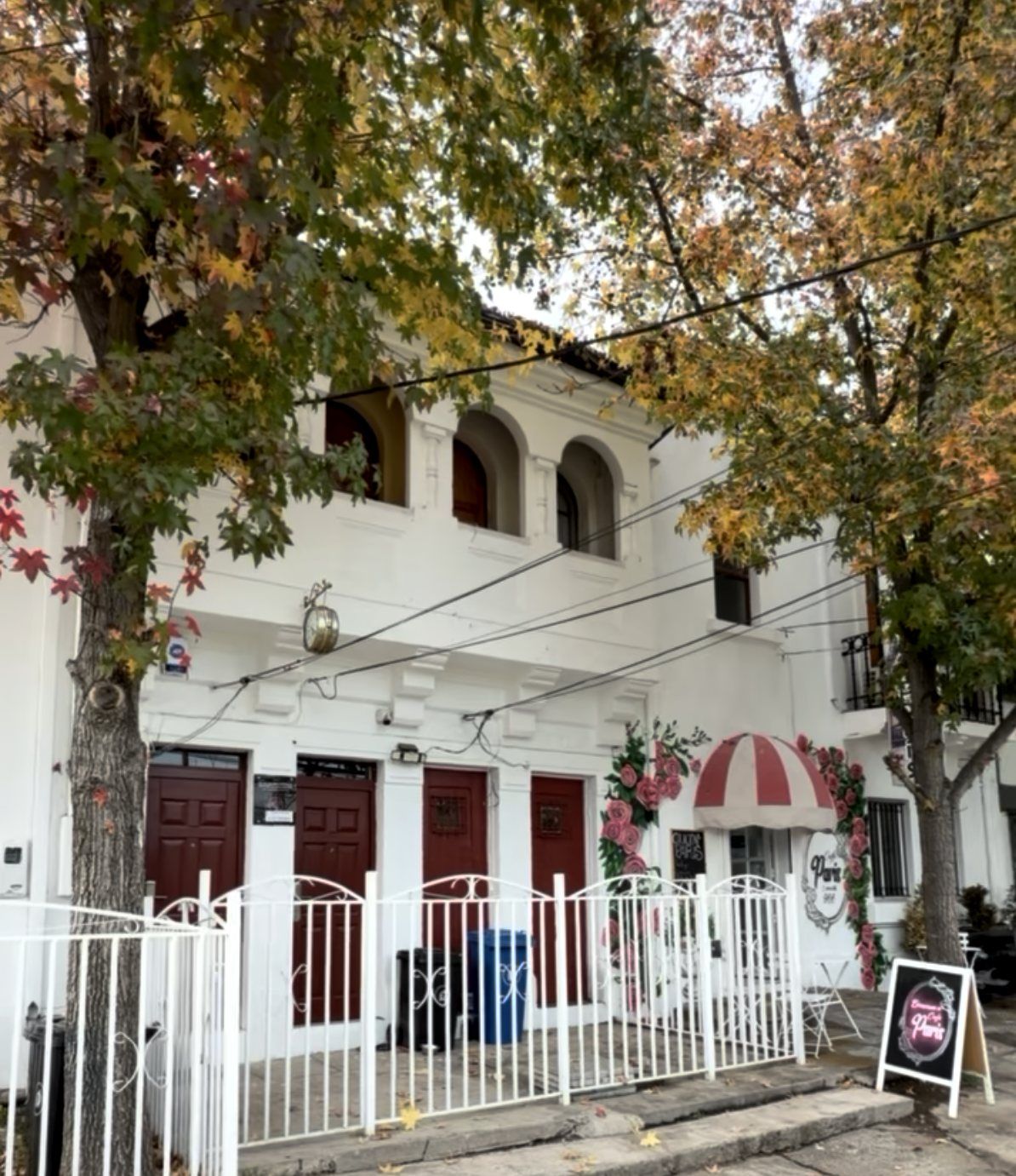 Fachada de día de la casa patronal, con arcos, puertas rojas y la entrada del café